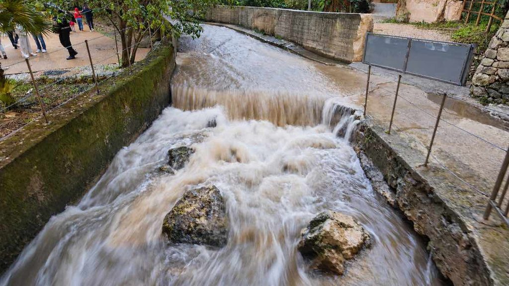 Il torrente si ingrossa mentre i primi ragusani scendono nella Cava Santa Domenica. La corrente non li scoraggia: i ponticelli metallici consentono di attraversarlo in sicurezza. Foto V. Sottosanti / Archivio LIMEN.